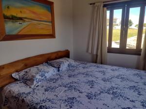 a bedroom with a bed and a painting and a window at Refúgio do Jaguari in Piracaia