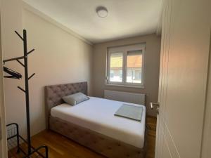 a small bedroom with a bed and a window at Apartman Laki in Bijeljina +3 photos