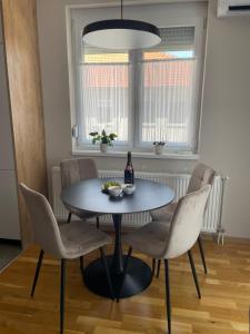 a dining room table with chairs and a bottle of wine at Apartman Laki in Bijeljina