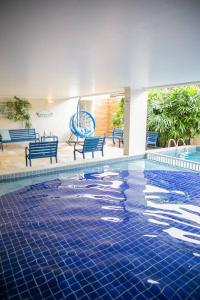 a swimming pool with blue benches in a building at Pousada Villa Di Enzo in Ubatuba