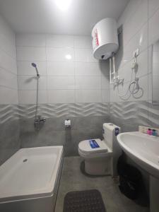 a bathroom with a white toilet and a sink at Baxt Hotel&Hostel in Andijan