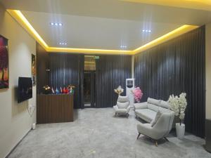 a lobby with a couch and two chairs and a tv at Baxt Hotel&Hostel in Andijan