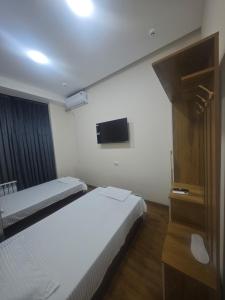 a bedroom with two beds and a tv on the wall at Baxt Hotel&Hostel in Andijan +9 photos