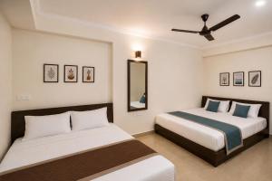 a bedroom with two beds and a ceiling fan at Sunlight Stay at Goa in Calangute