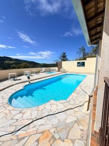 a swimming pool in a yard with a stone patio at Pousada Caminho das Aguas in Lindóia