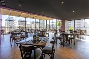a restaurant with tables and chairs and large windows at Intercity Faria Lima Address in São Paulo