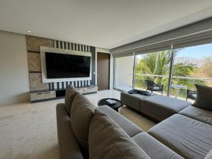 a living room with a couch and a flat screen tv at Departamento Diamante Azul Punta Mita, Beach Front in Punta Mita