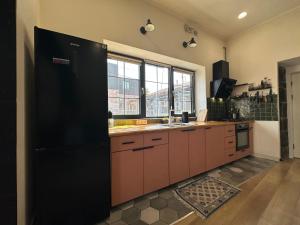 a large kitchen with a large black refrigerator at Communa Guesthouse in Gyumri