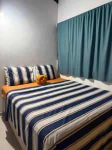 a bedroom with a large bed with a blue curtain at Refúgio a 100m da Praia Conforto e Lazer Completo in Prado