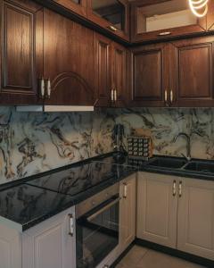 a kitchen with wooden cabinets and marble counter tops at Villa Bushati in Tropojë +10 photos