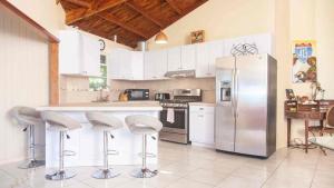 a kitchen with white cabinets and a counter with stools at Tres Amigos Beach House, Rincon PR in Rincon