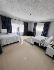 a large bedroom with two beds and curtains at BillGates BNB in Harare +2 photos