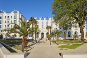 a large white building with palm trees in front of it at Petit gîte du nouguès in Garrey