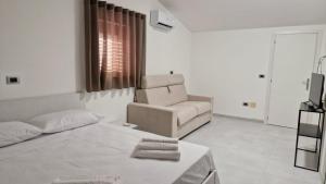 a white room with a bed and a chair at Il cedro blu in Santa Maria del Cedro