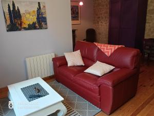a red leather couch in a living room with a table at La Cadournaise in Saint-Seurin-de-Cadourne