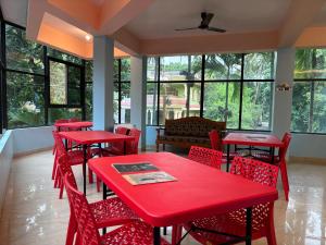 a restaurant with red tables and chairs and windows at Colors Fly Hotel in Colva