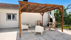 a patio with white chairs and a wooden pergola at Villa Madalena in Coucieiro