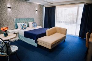 a bedroom with a bed and a chair and a window at Avenue Nizami hotel in Baku