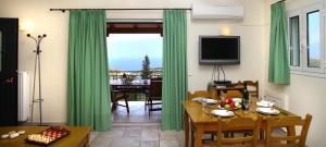 a living room with green curtains and a dining room at Liogerma Villas in Agios Nikitas