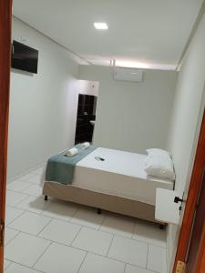 a bedroom with a bed in a white room at Pousada Panorama Palace in Santa Maria da Vitória