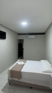 a bedroom with a large white bed in a room at Pousada Panorama Palace in Santa Maria da Vitória