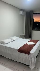 a bed in a white room with a window at Pousada Panorama Palace in Santa Maria da Vitória