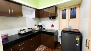 a kitchen with brown cabinets and a black refrigerator at R S Homestay in Deoghar