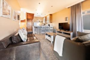 a living room with two leather couches and a kitchen at Lagoon View Self Catering in Walvis Bay