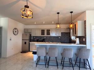 a kitchen with white cabinets and a bar with stools at Sea-Renity in Philipsburg