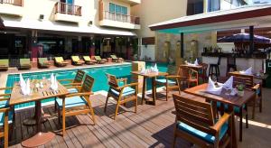 a restaurant with tables and chairs next to a swimming pool at Sarita Chalet & Spa Jomtien beach Pattaya in Jomtien Beach