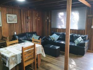 a living room with a black leather couch and a table at Casa do Campo in Ilha do Mel