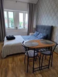 a bedroom with a bed with a table and chairs at Kameralny Apartament w Centrum in Szczytno