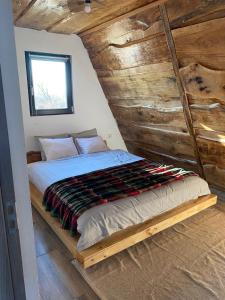 a bed in a room with a wooden wall at Feeria Land Aframe in Radoşi