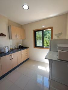 a kitchen with wooden cabinets and a window at O LAR DO SIL - Ribeira Sacra in Villar de Cerreda