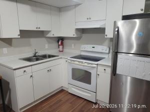 a kitchen with white cabinets and a stainless steel refrigerator at Private 2 bedroom suite close to everything! in Maple Ridge