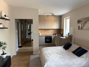 a bedroom with a white bed and a kitchen at Apartament Żurawie in Jastrowie