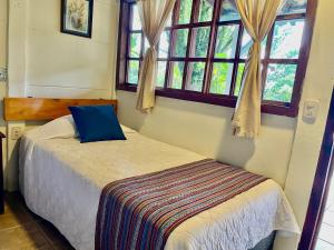 a bedroom with a bed and two windows at cabañas de Apaneca in Apaneca