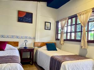 two beds in a room with two windows at cabañas de Apaneca in Apaneca