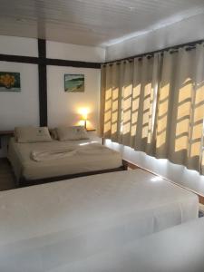 a bedroom with two beds and a window at Barla Inn Suites in Búzios