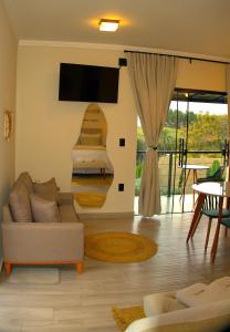 a living room with a couch and a tv at Angatu Chalés in Serra Negra