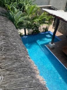 a blue swimming pool with a table and palm trees at Villa del Mar in Zipolite