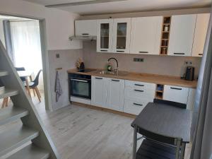 a kitchen with white cabinets and a sink and a table at Chata Rumunka in Jaroměř
