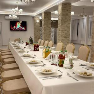 a long table in a room with white tables and chairs at Górski Ośrodek Pod Kamiennikiem in Poręba