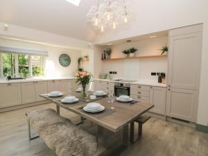 a kitchen with a wooden table and a dining room at 12 Manor Farm Close in Kingham +12 photos