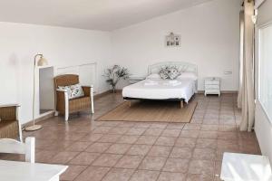 a white bedroom with a bed and a chair at Villa Nispero in El Tosalet +9 photos