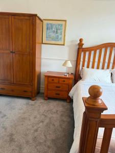 a bedroom with a wooden bed and a dresser with a lamp at The Strand Hotel in Bournemouth +4 photos