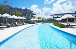 a pool at a resort with chairs and umbrellas at Blue Coast Condo in Puerto Plata
