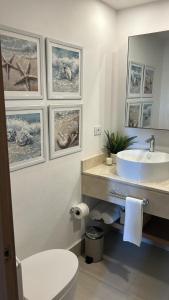 a bathroom with a sink and a toilet and pictures on the wall at Blue Coast Condo in Puerto Plata +24 photos