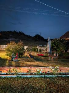 two people sitting in a yard with a playground at Etno Kuća Jaćimović 1 in Pranjani
