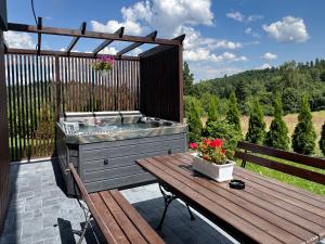 a deck with a hot tub and a wooden table at Agroturystyka Nad Lasem - Domki w górach in Toporzysko